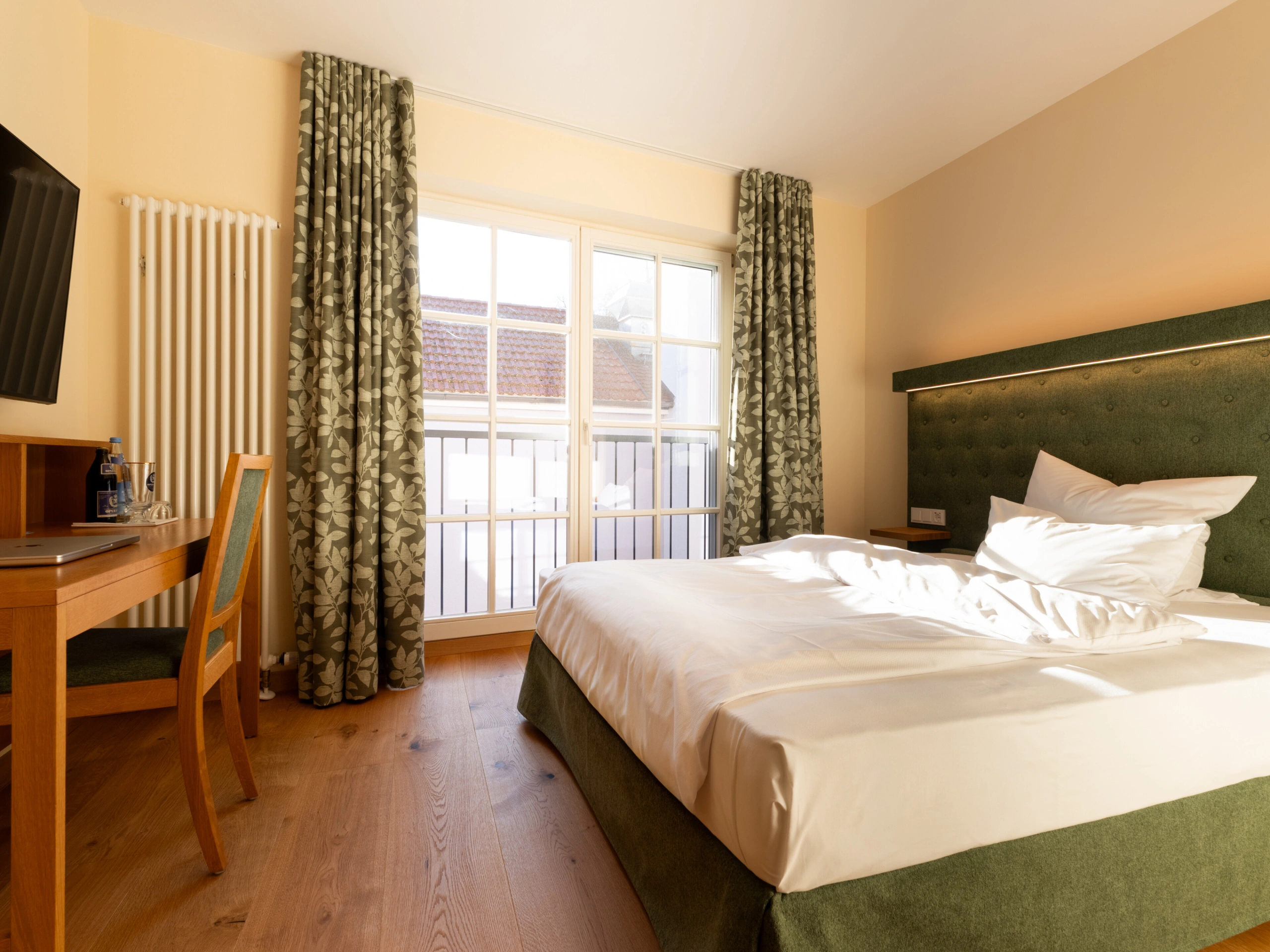 Dachgarten-Doppelzimmer mit Doppelbett, Schreibtisch und Fenstertür zum Balkon