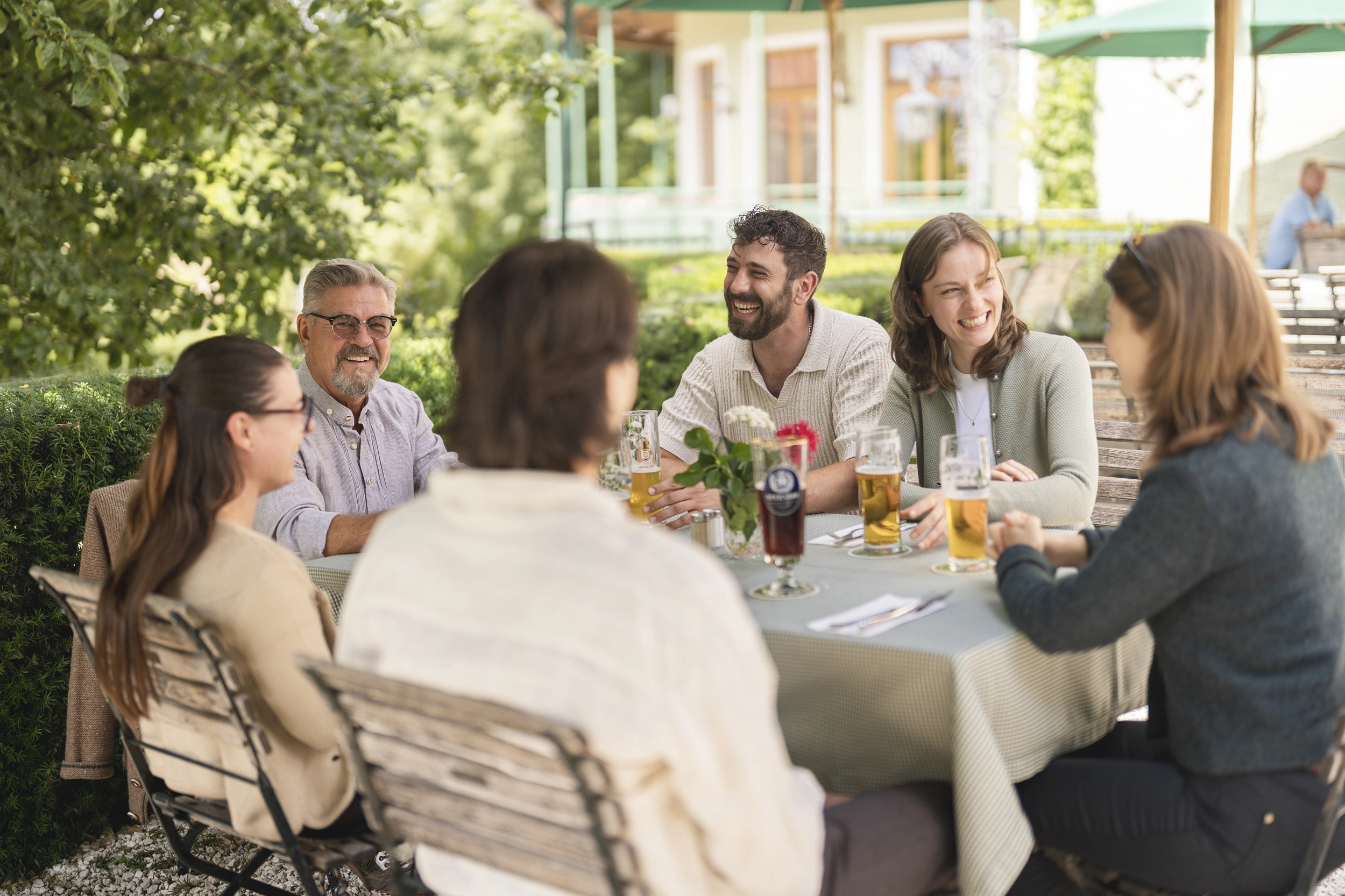 Freundesgruppe feiert an einem gedeckten Tisch im Biergarten