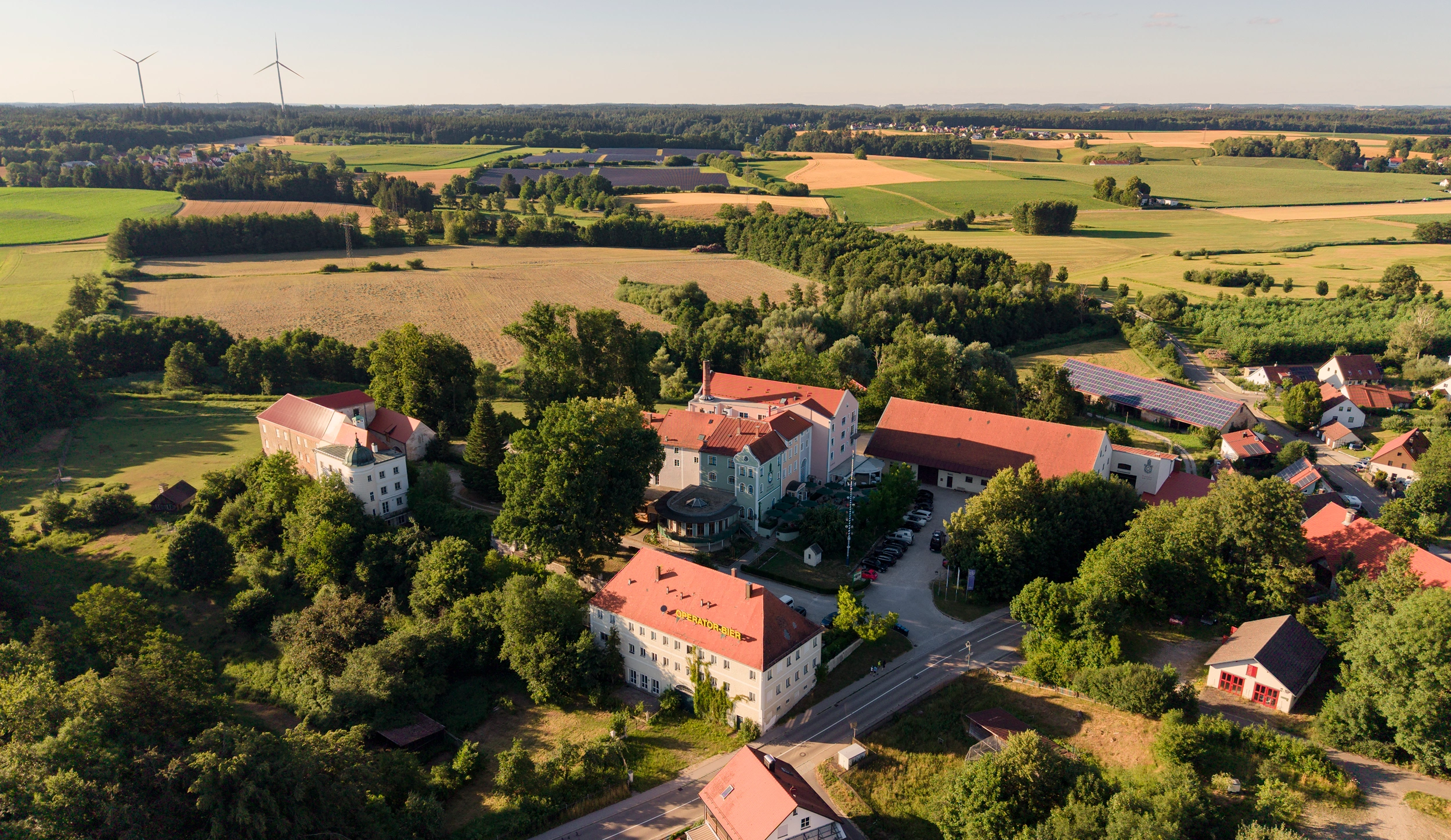 Luftaufnahme des Schlossguts Odelzhausen inmitten von Feldern und Wäldern