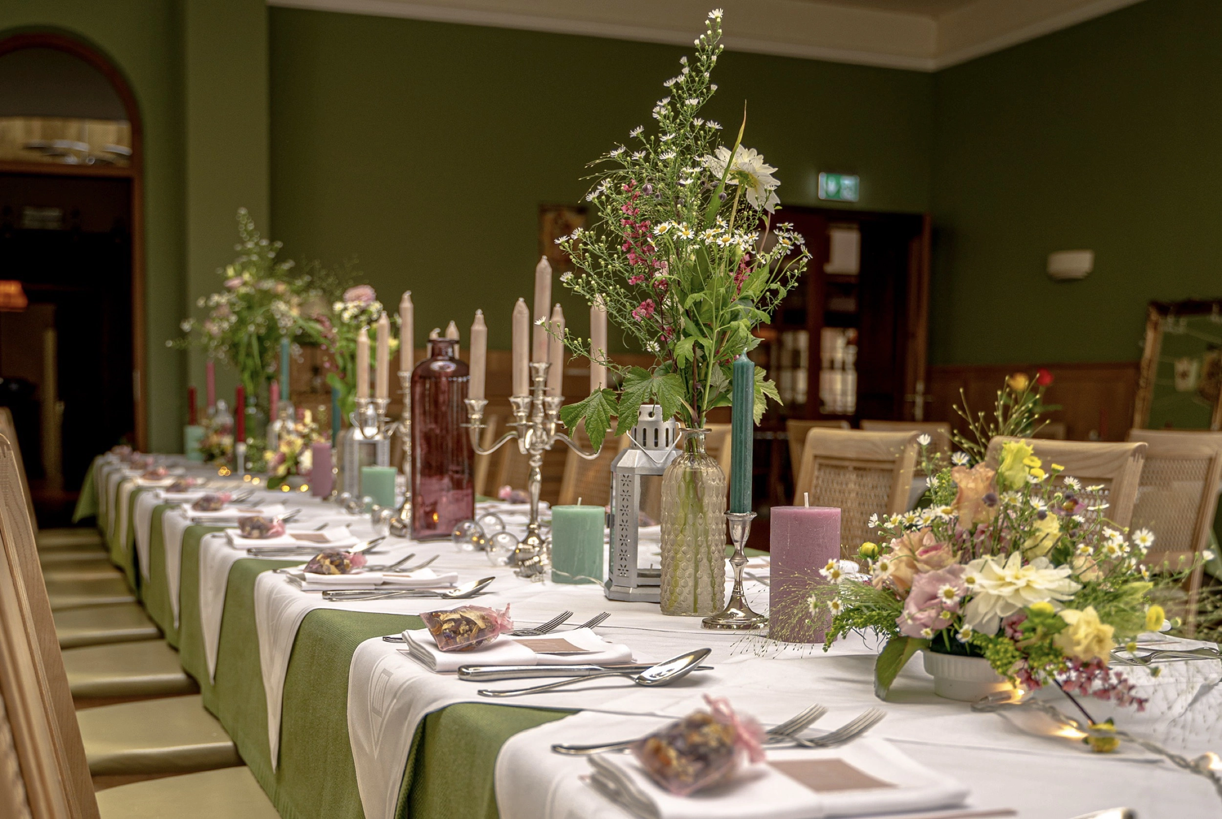 Festlich gedeckte Tafel mit Kerze, Weingläsern und Blumenstrauß